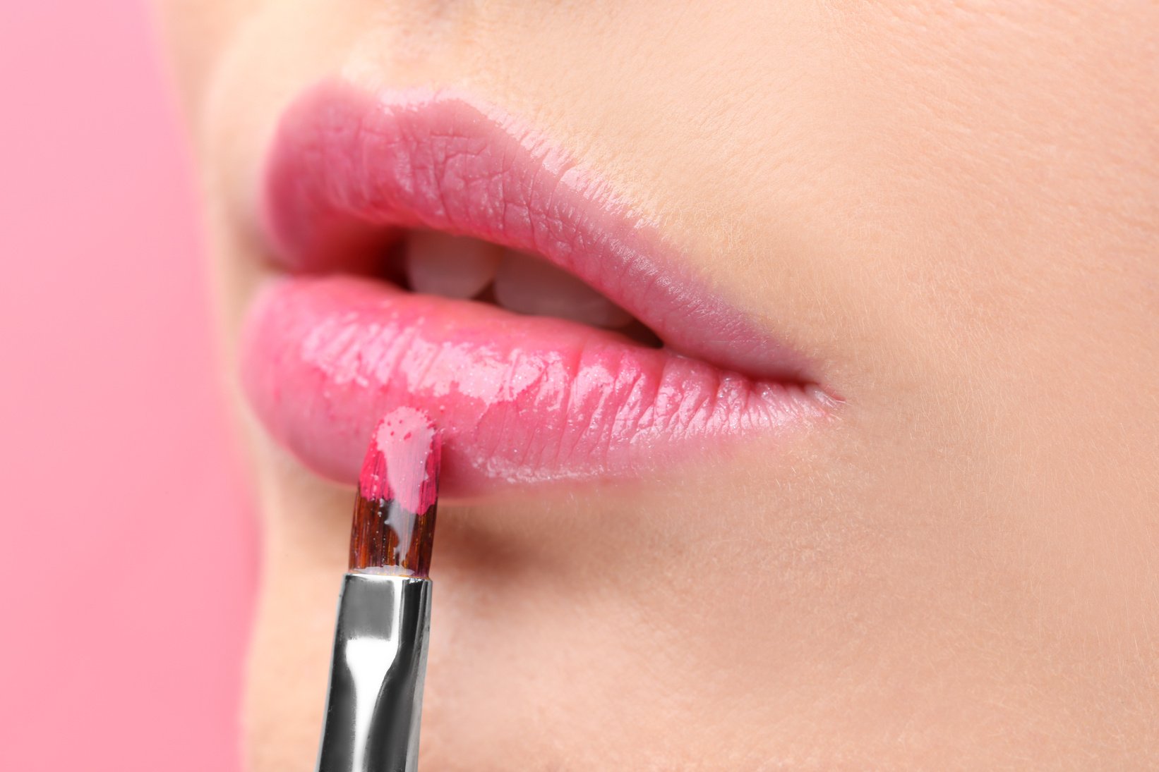 Young Woman Applying Pink Gloss on Lips